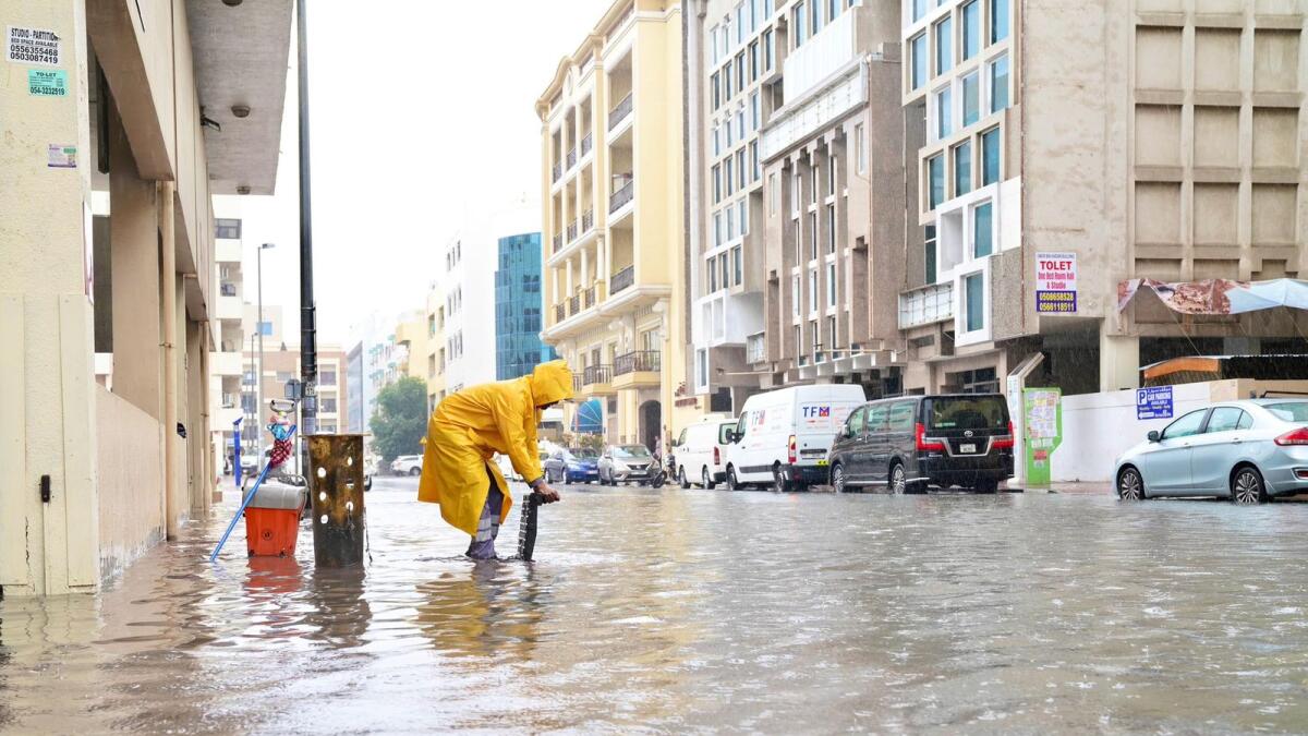 A Dubai Municipality employee works to clear the water from a street after heavy rains on Saturday. — Photos: Supplied