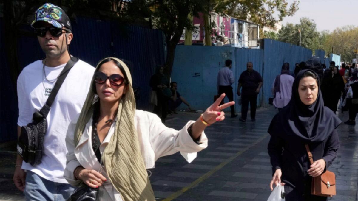 A woman flashes a victory sign as she walks around in the old main bazaar of Tehran. — AP