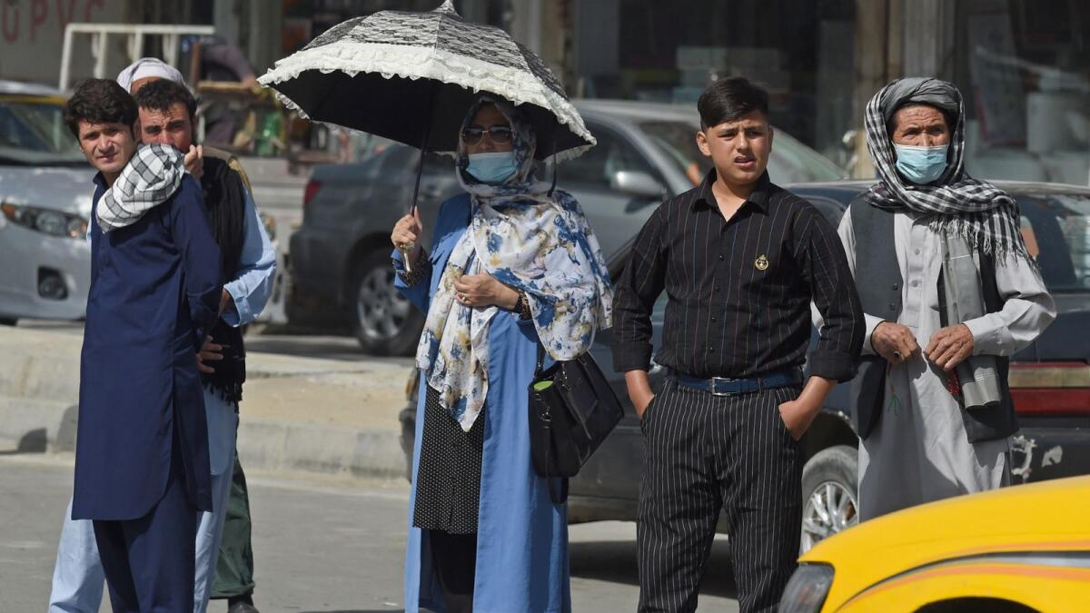 Afghan people stand along the roadside in Kabul. Photo: AFP
