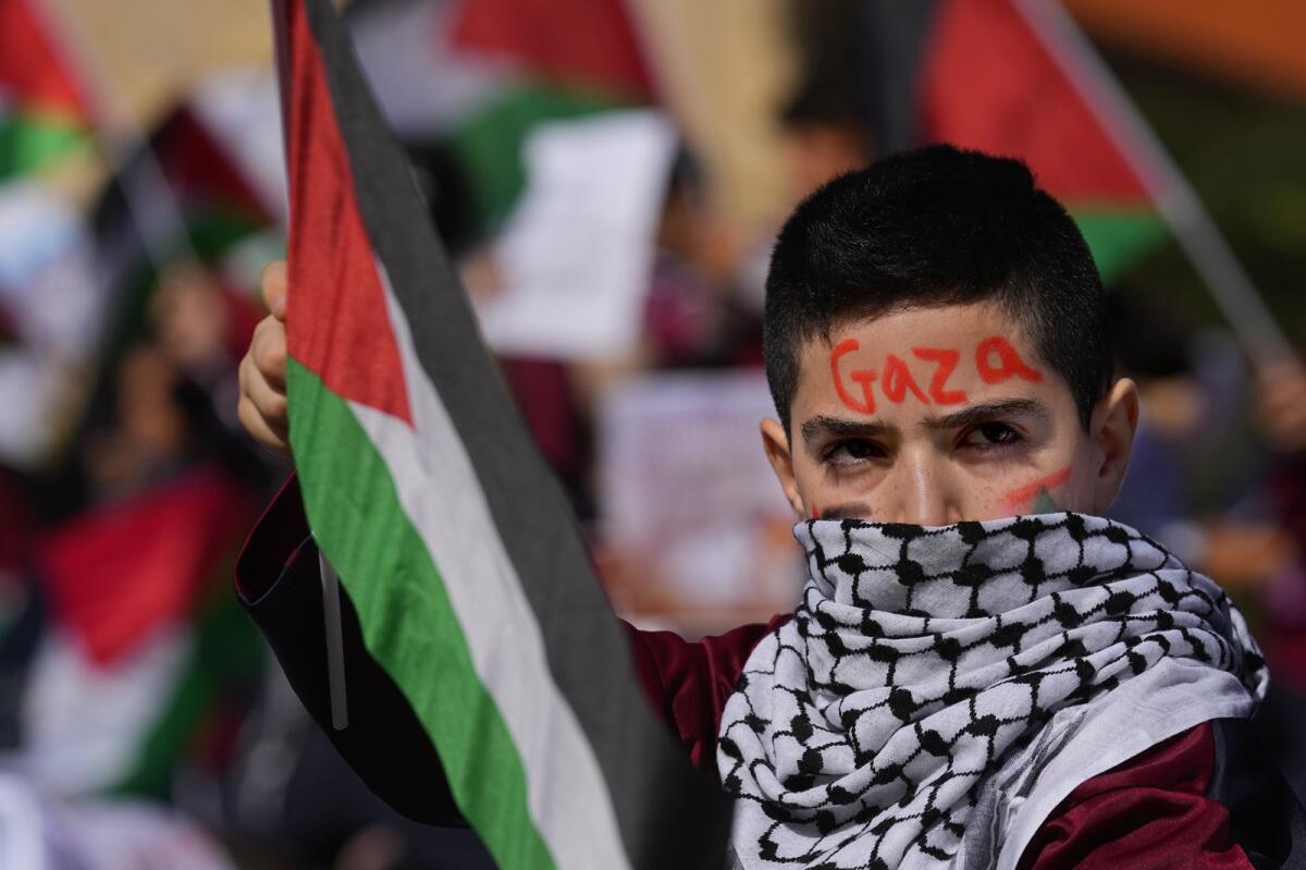 A boy holds a Palestinian flag during a protest against Israel's attack on the Gaza Strip. Nov. 21, 2023. Photo: AP