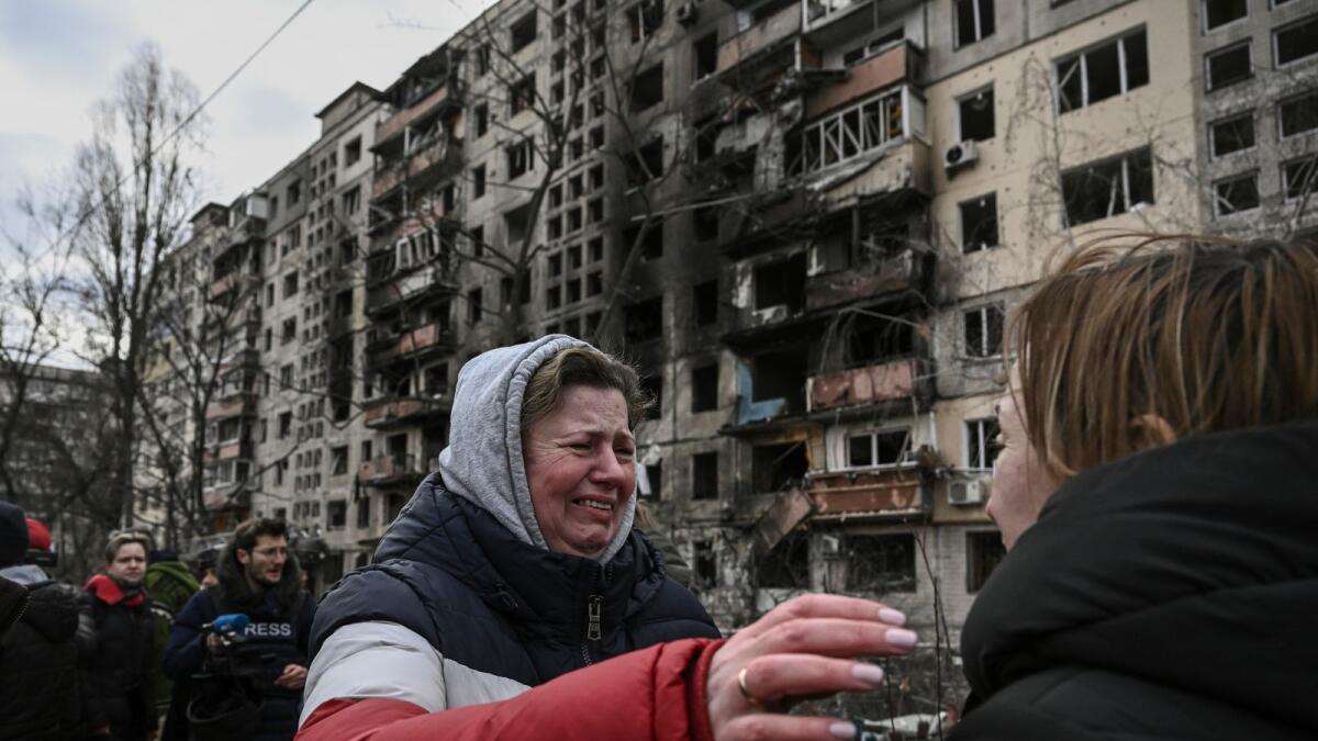 A woman reacts as she stands outside destroyed apartment blocks following shelling in the northwestern Obolon district of Kyiv on March 14, 2022. Photo: AFP