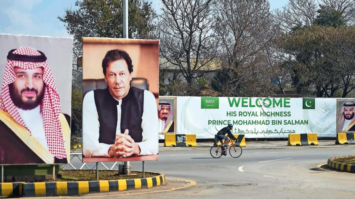 A cyclist rides past billboards showing portraits of Saudi Arabia’s Crown Prince Mohammed bin Salman and Pakistan’s Prime Minister Imran Khan and a banner welcoming the prince ahead of his arrival in Islamabad. — AFP
