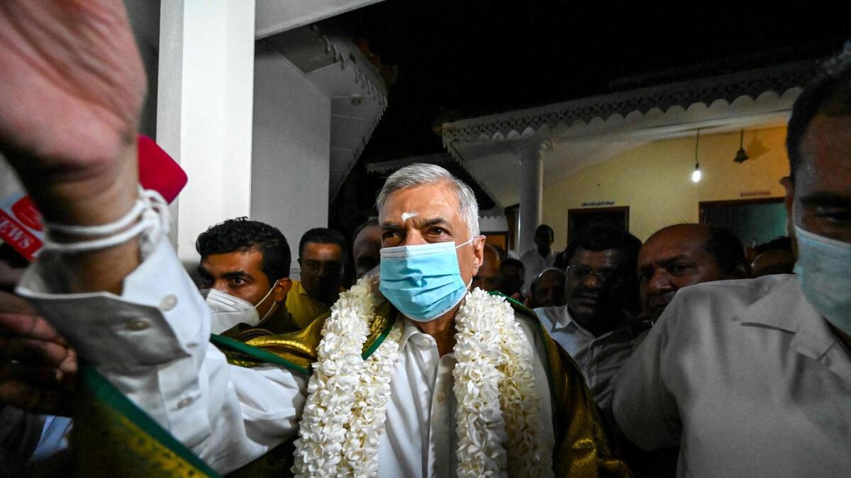 Sri Lanka's new prime minister Ranil Wickremesinghe (C) visits a Buddhist temple after his swearing in ceremony in Colombo on May 12, 2022. Wickremesinghe was sworn in as Sri Lanka's prime minister for the sixth time on May 12, 2022 though the veteran politician has never completed a full term in office. (Photo by Ishara S. KODIKARA / AFP)