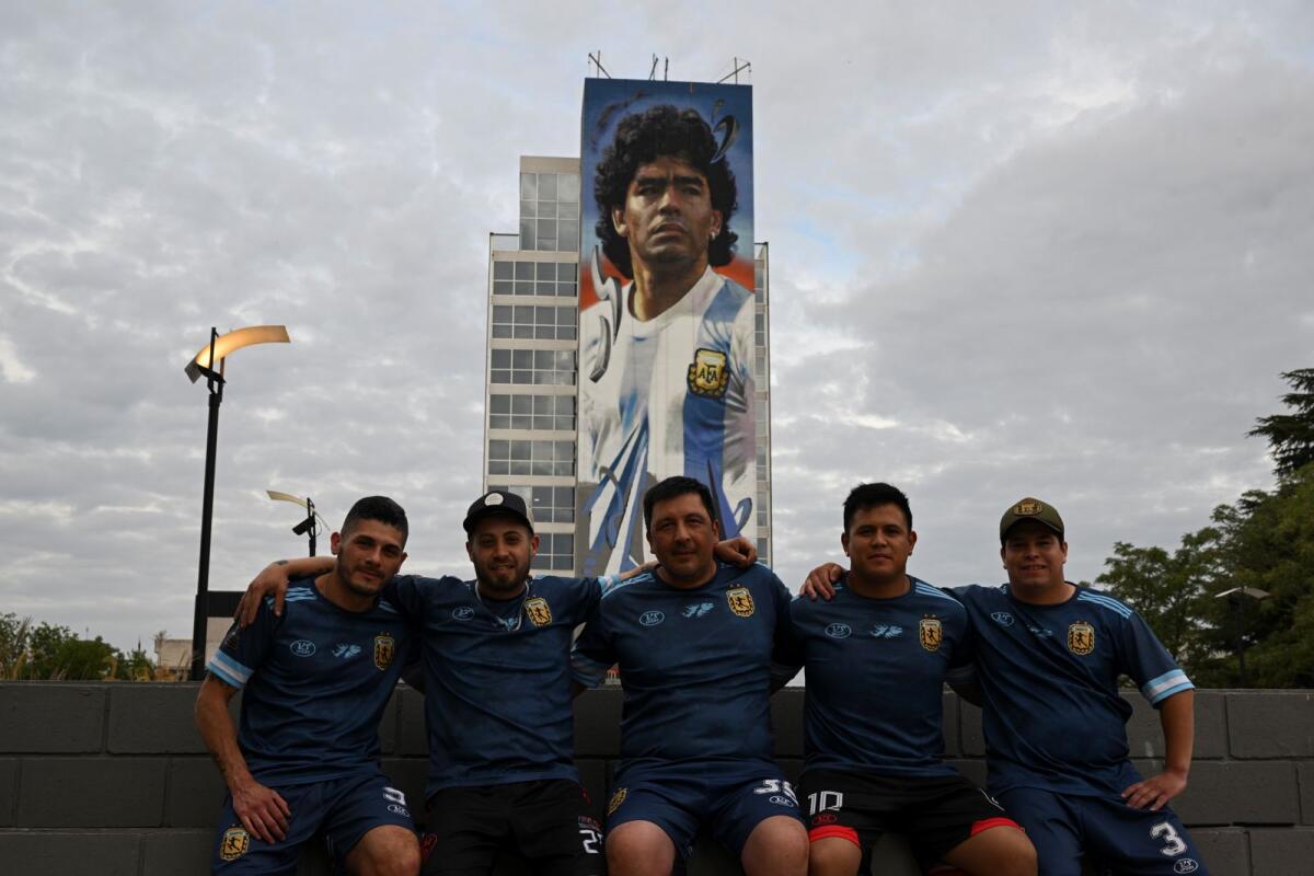 Fans of late Argentine football legend Diego Maradona poses for a photo in front of a mural in Buenos Aires, Argentina. (AFP)
