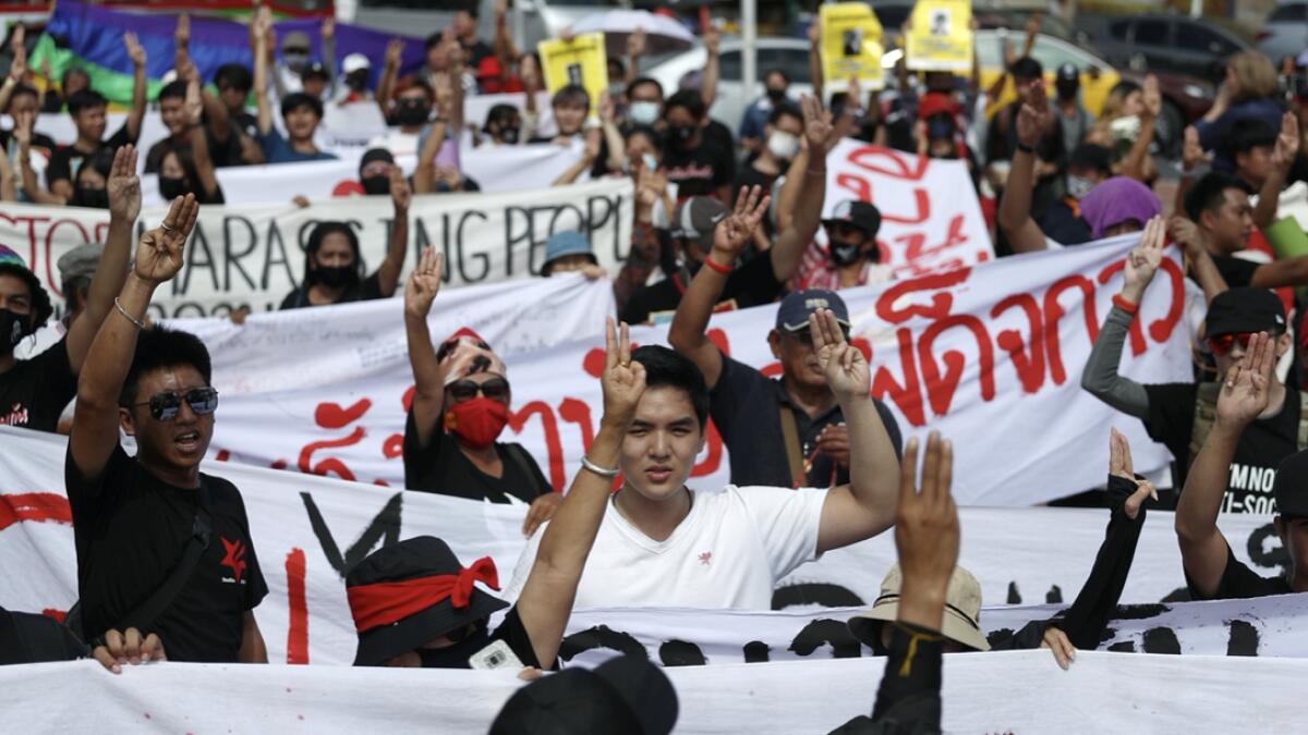 Pro-democracy protesters display the three-finger salute and hold a banner during a rally in Bangkok, Thailand. Photo: Reuters