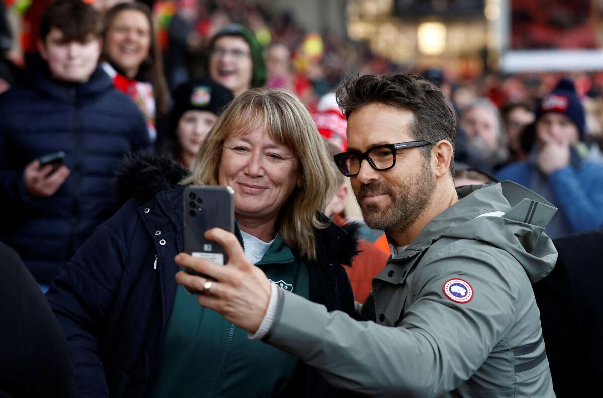 Wrexham co-owner Ryan Reynolds poses with a fan for a picture before the match