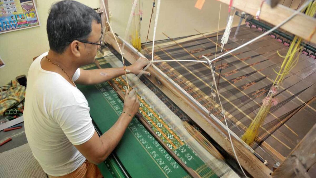 An artisan weaves fabric on a handloom at his household workshop at Koyalagudem village, near Hyderabad. 