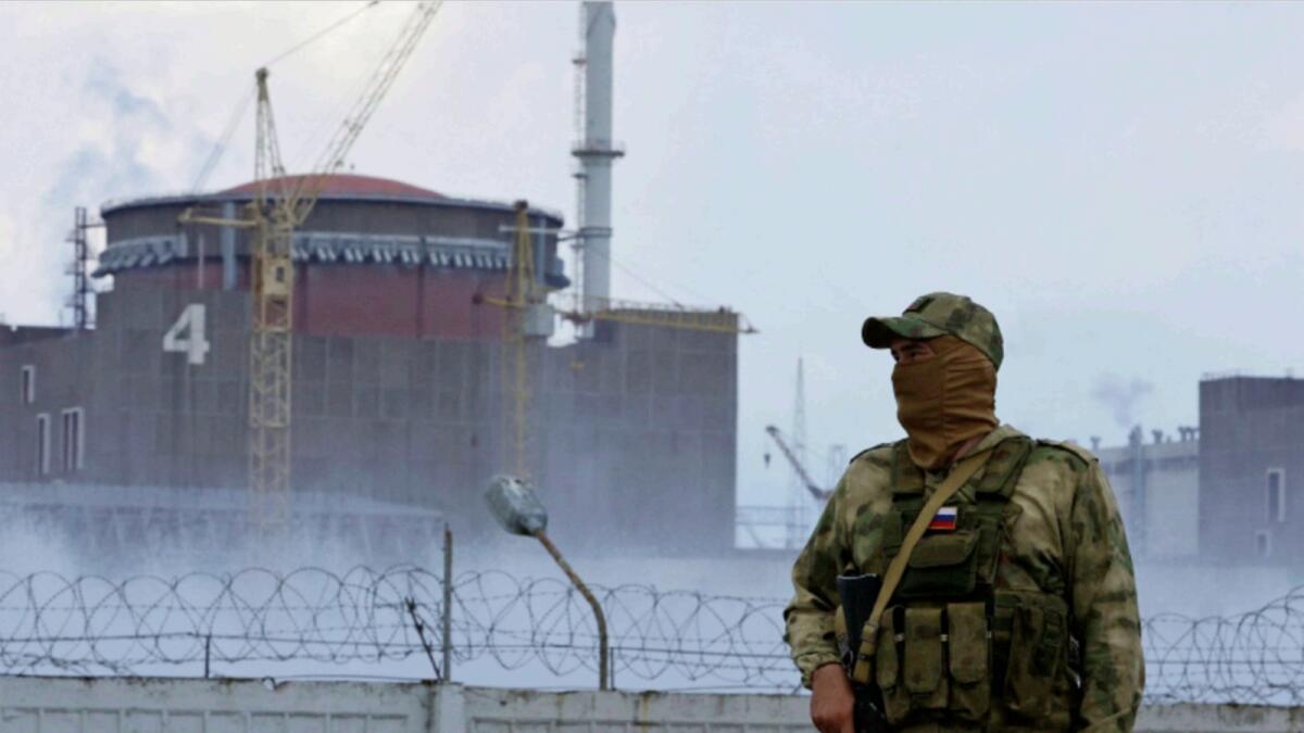 A serviceman with a Russian flag on his uniform stands guard near the Zaporizhzhia nuclear power plant. — Reuters
