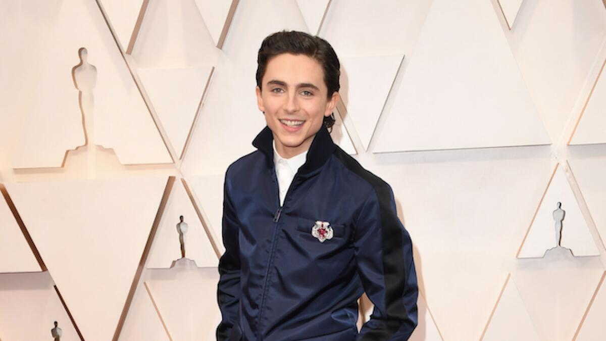 Timothée Chalamet detoured from a slew of classic black tuxedos in a custom Prada navy gabardine jacket with satin racing stripes and matching trousers.