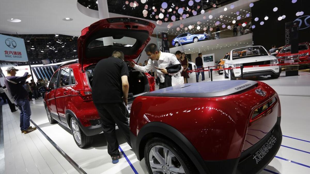 Visitors examine the Chinese automaker Baic EX200 powered by solar energy on display at the Beijing International Automotive Exhibition on Monday. 