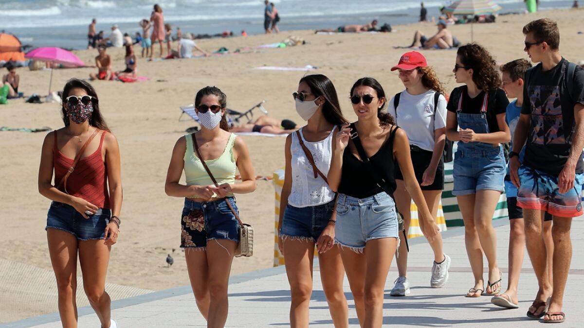 People wear face masks as they walk near the beach in Biarritz, southwestern France. Face masks are now obligatory in France's supermarkets, shopping malls, banks, stores, and indoor markets, to curb worrisome signs that the coronavirus is making inroads again. Photo: AP