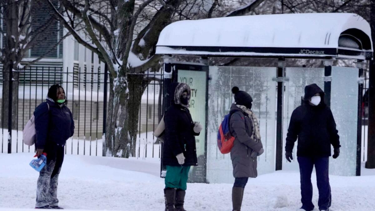 Commuters wait in the street for a Chicago Transit Authority bus in the Bronzville neighbourhood of Chicago. A winter storm has blanketed the Chicago area overnight with up to 18.5 inches of snow. — AP