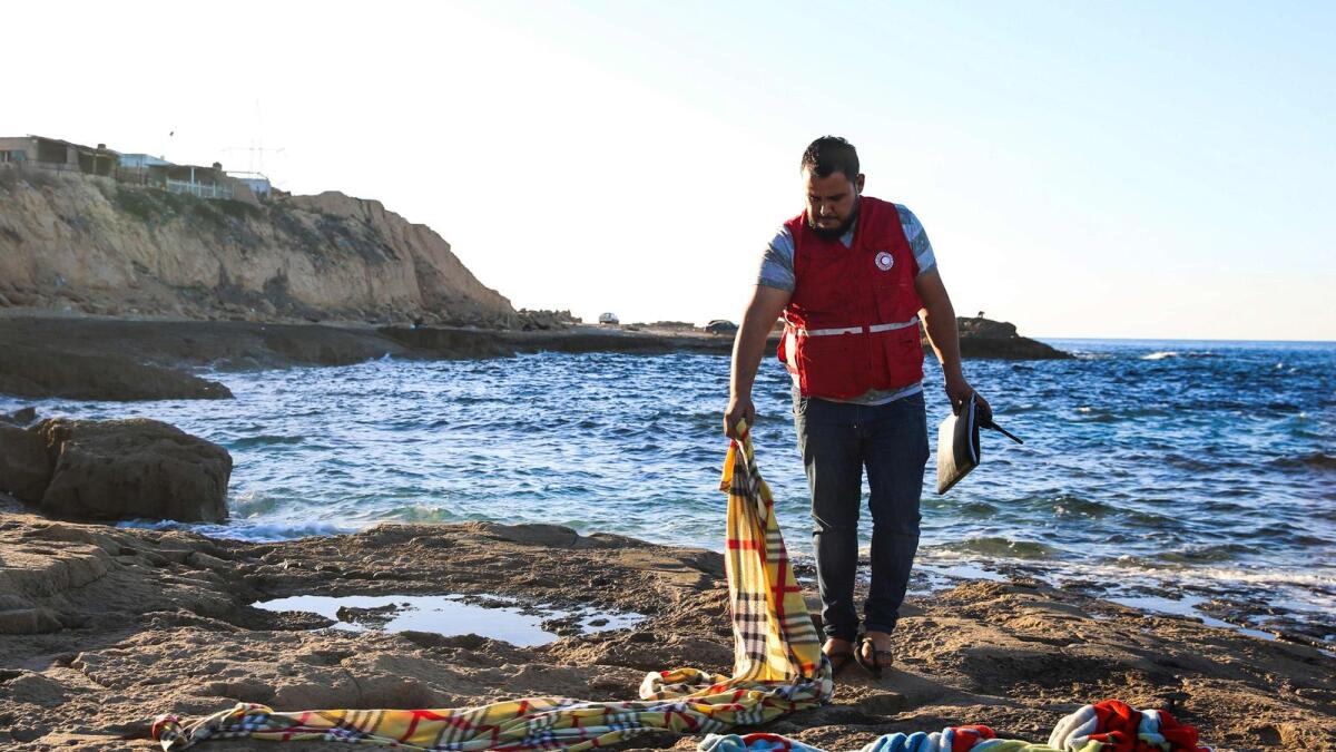 A member of the Libyan Red Crescent checks blankets in which the bodies of drowned migrant children were wrapped on the shore of Zawia, west of the Libyan capital Tripoli, after the corpses were transported to a nearby hospital morgue, on December 16, 2020.