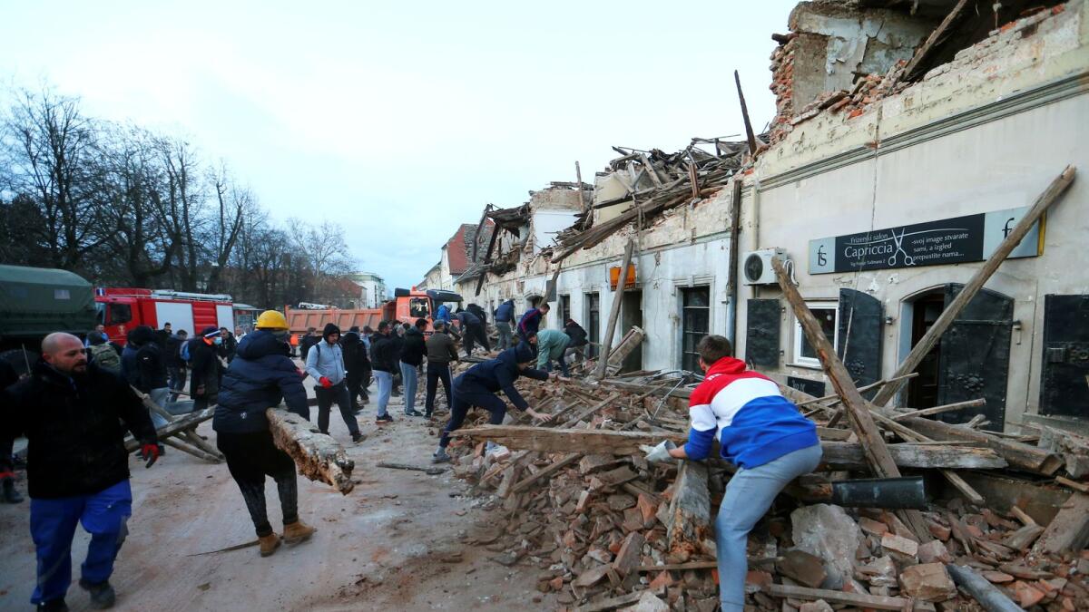 People clean debris after an earthquake, in Petrinja, Croatia. Reuters