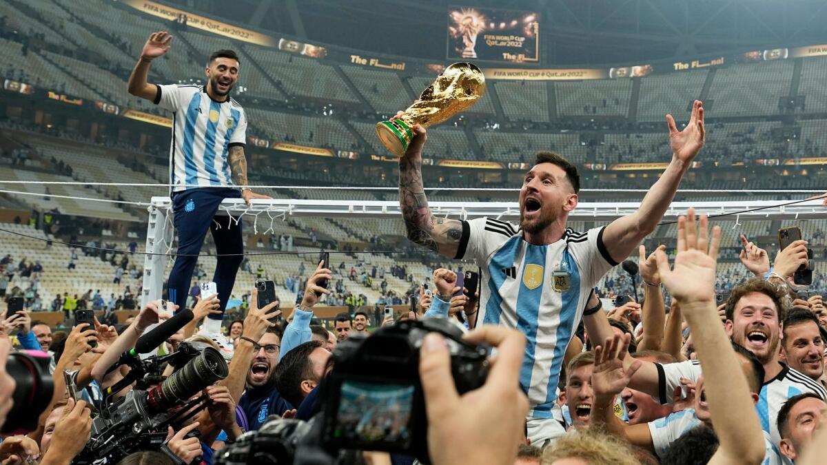 Argentina's Lionel Messi celebrates with the trophy in front of the fans after winning the World Cup final match between Argentina and France. — AP
