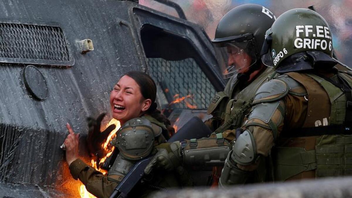 A riot police officer on fire reacts during a protest against Chile's government in Santiago, Chile November 4, 2019. As the police used tear gas canisters and water cannon against protesters, a series of Molotov cocktails were thrown in the direction of the police. Two officers were engulfed in flames. They were helped by colleagues who used fire extinguishers and their hands to put out the fires. - Reuters
