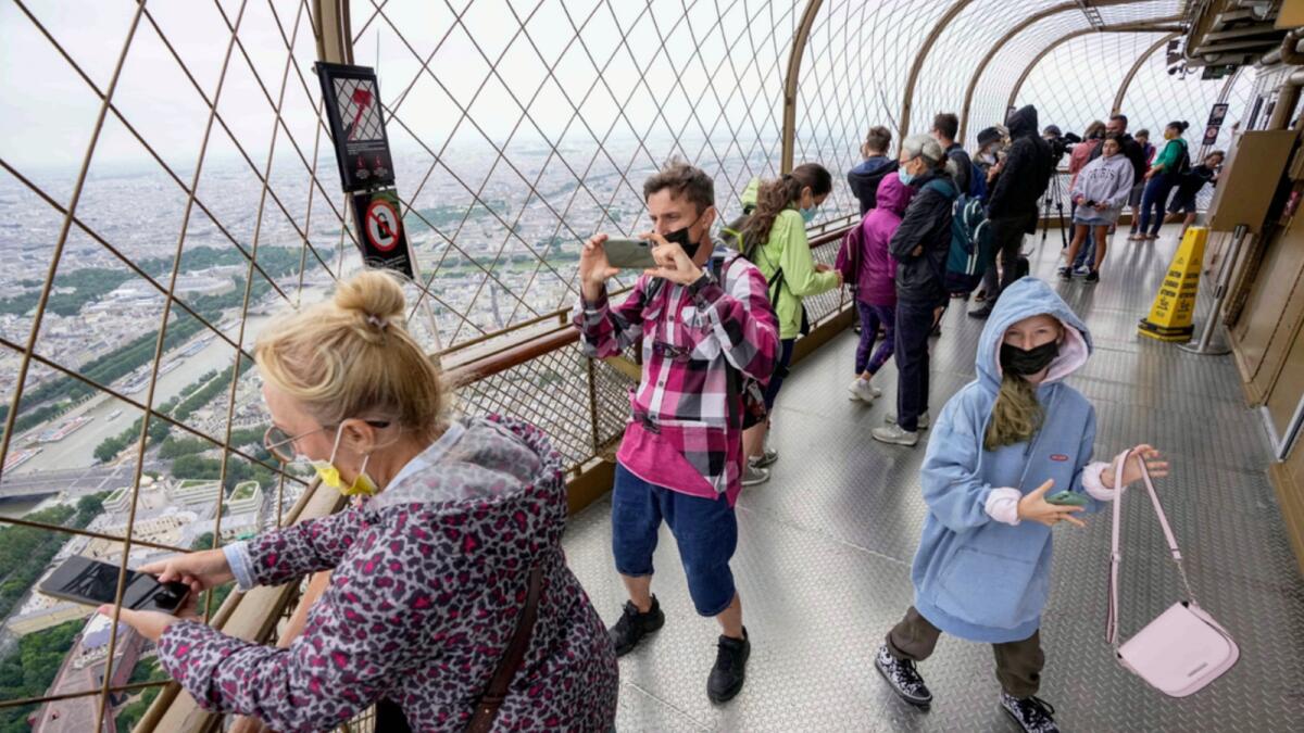 Visitors enjoy the view from top of the Eiffel Tower in Paris. — AP file