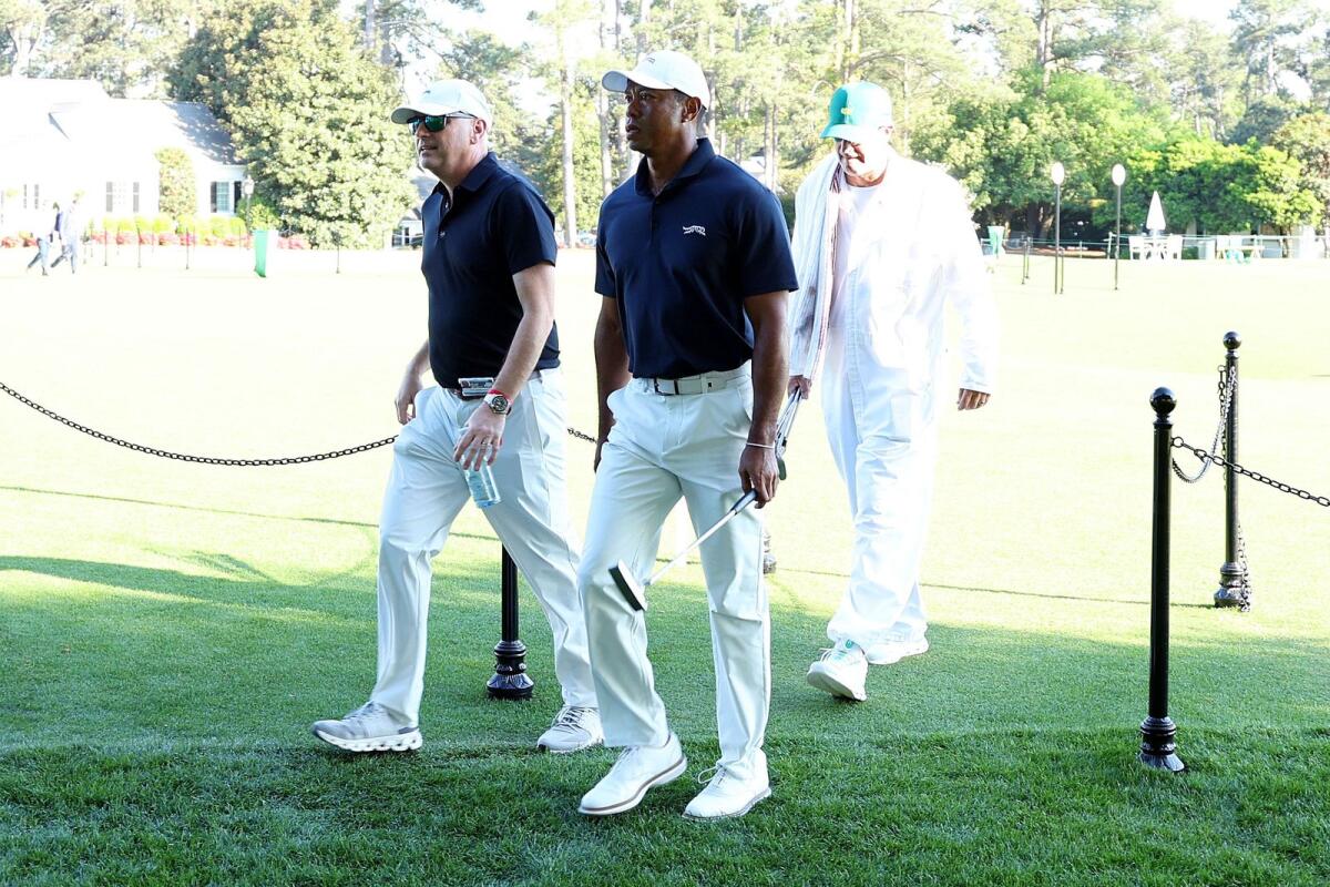 Tiger Woods leaves the course to enter the Clubhouse after practising a few holes with Rob McNamara and caddie Lance Bennett. — AFP