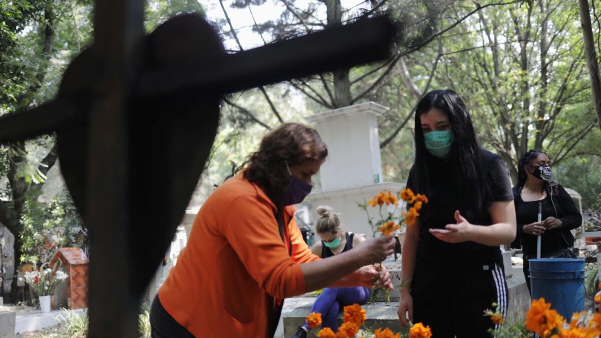 Family members decorate the grave of a relative at the Xilotepec cemetery in the lead-up to the Day of the Dead celebration, in Xochimilco on the outskirts of Mexico City, Mexico October 28, 2020. Picture taken October 28, 2020.