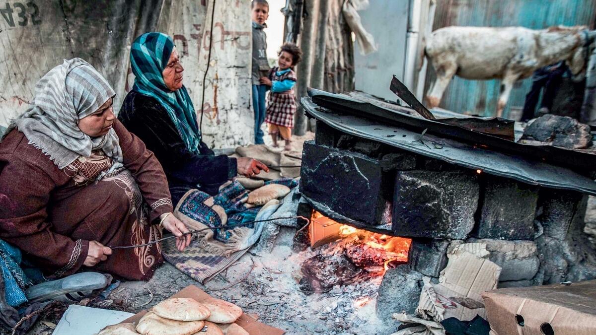 Palestinian women bake bread next to their makeshift home in a refugee camp in the southern Gaza Strip. The only functioning power plant in the area has been out of action.—AFP