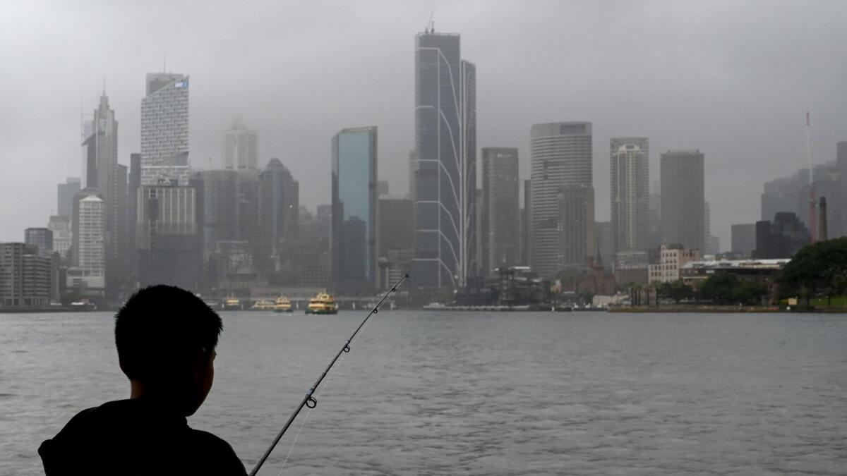 A man fishes in the harbour while it rains in Sydney on October 6, 2022. -- File photo