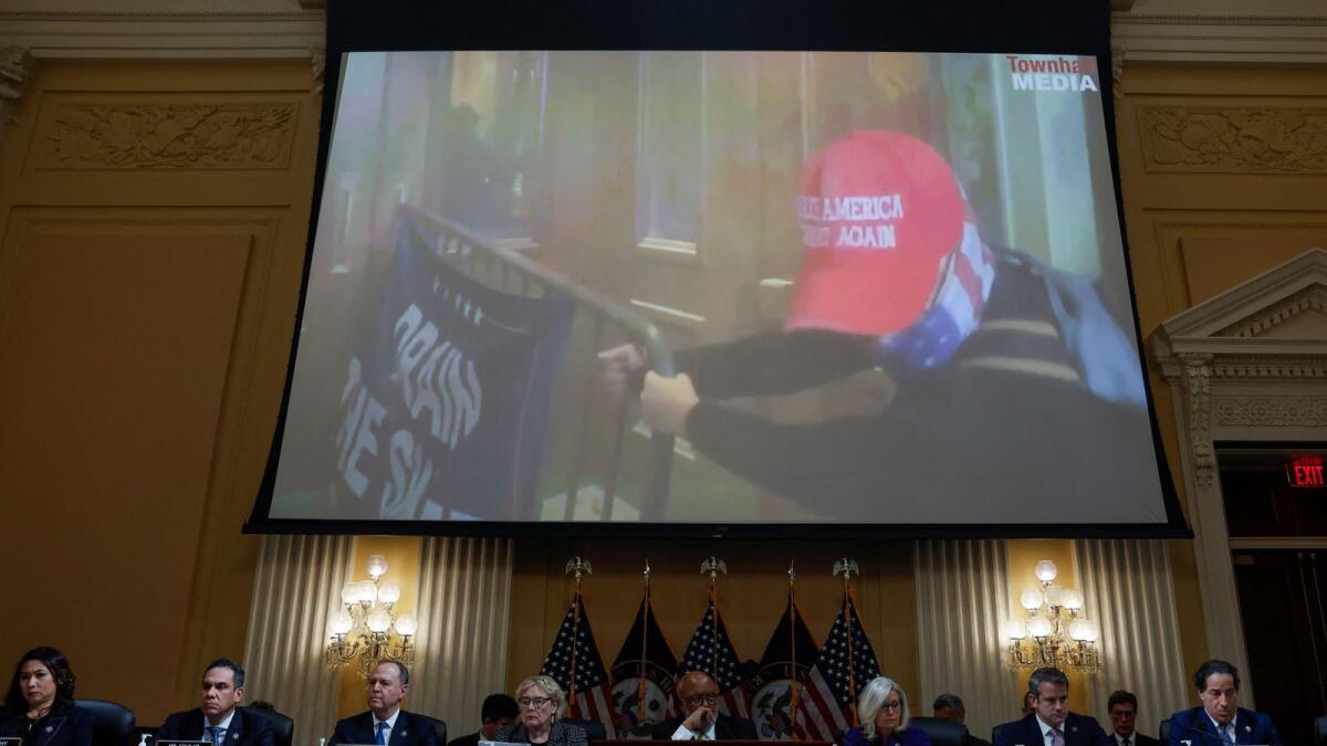 Members of the US House Select Committee investigating the January 6 Attack on the US Capitol sit beneath an image showing a supporter of former US president Donald Trump wearing a MAGA hat using a police barrier to attempt to break into the US Capitol as the committee holds their final public meeting to release their report on Capitol Hill in Washington on Monday. — Reuters