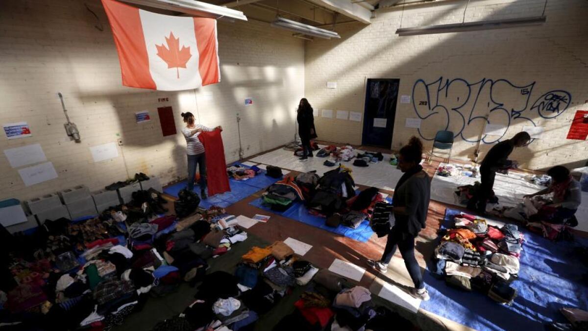 Clothing donated for an expected influx of Syrian refugees is sorted by volunteers for size and gender at a theater rehearsal space in Toronto.