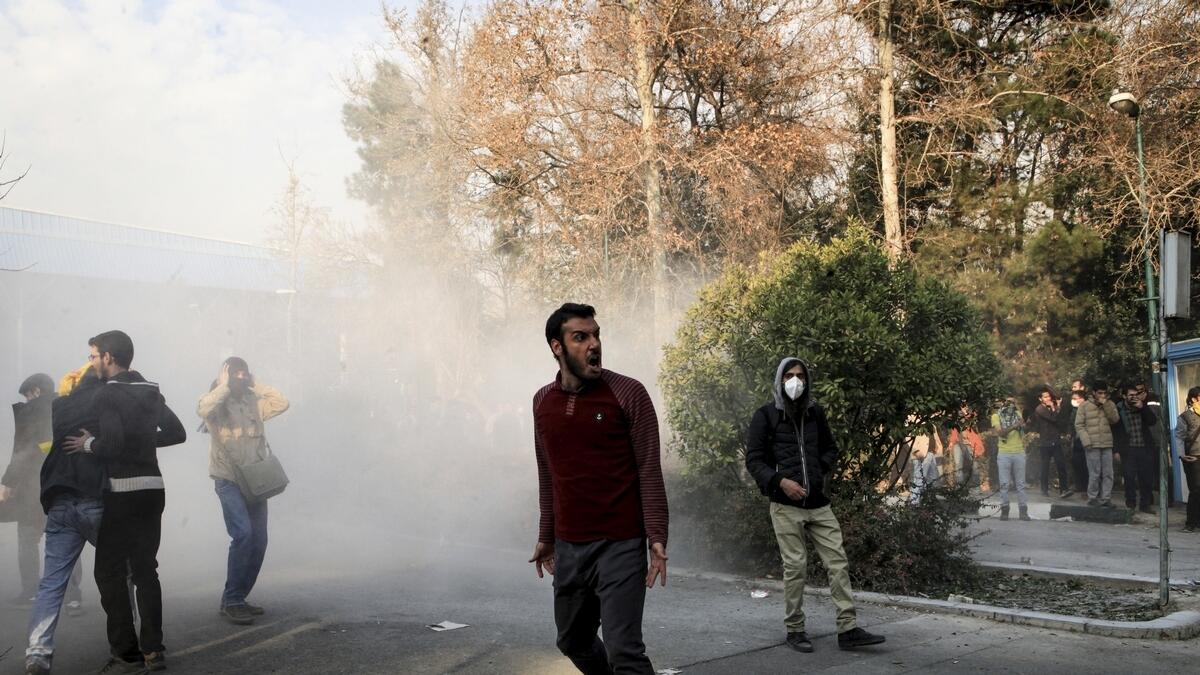 University students attend a protest inside Tehran University while a smoke grenade is thrown by anti-riot Iranian police.- AP