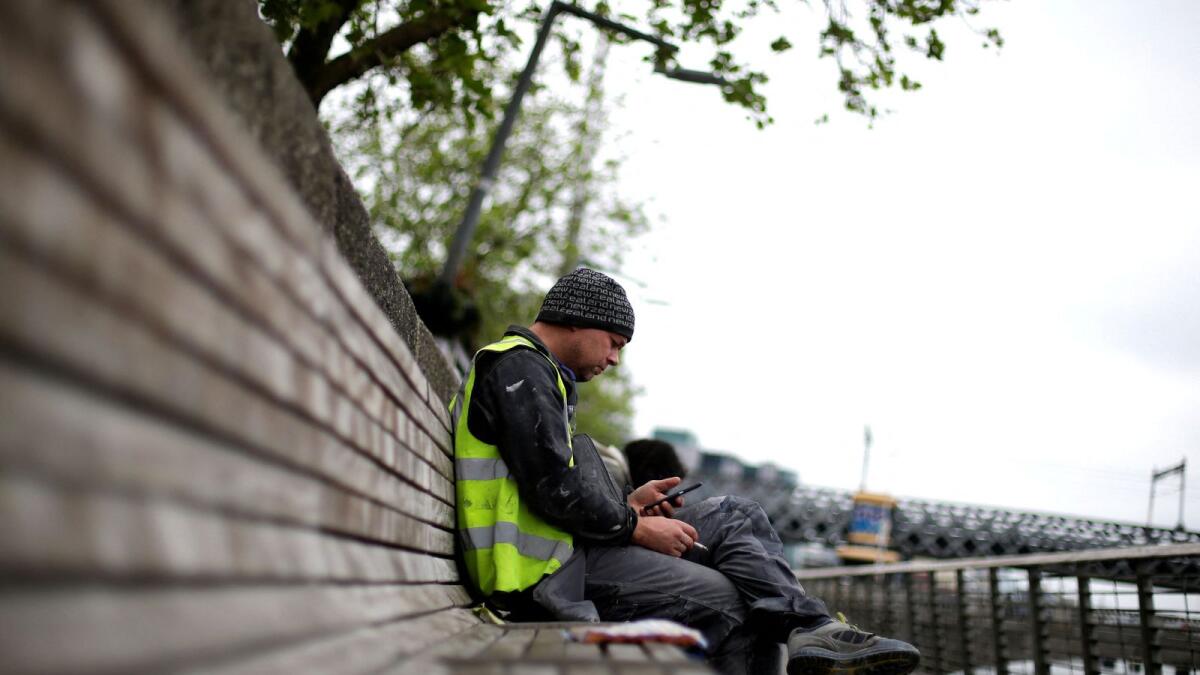 A man checks his phone in the city centre of Dublin, Ireland. Under the new EU rules, mobile software makers are required to show a choice screen where users can select a browser, search engine and virtual assistant as they set up their phones. — Reuters file