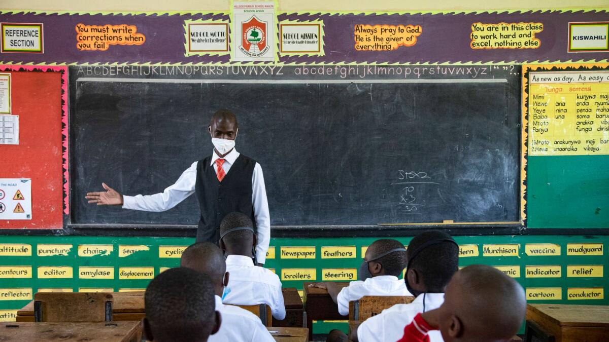 A teacher welcomes back students during a classroom lesson on day one of re-opening schools in Kampala, Uganda on January 10, 2022. Photo: AFP