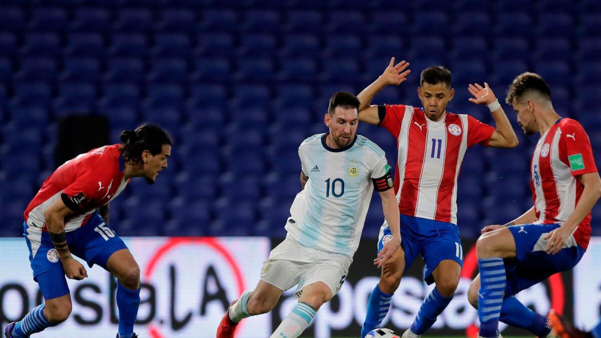 Argentina's Lionel Messi (centre) drives the ball next to Paraguay's Angel Romero (right) during their closed-door 2022 Fifa World Cup South American qualifier football in Buenos Aires. — AFP