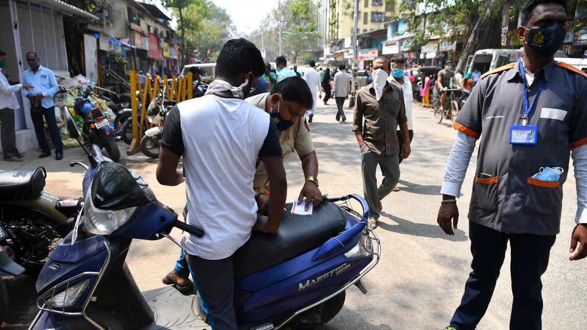 Civic authority marshals fine a motorcyclist for not wearing a face mask in Dharavi, Mumbai. Photo: AFP
