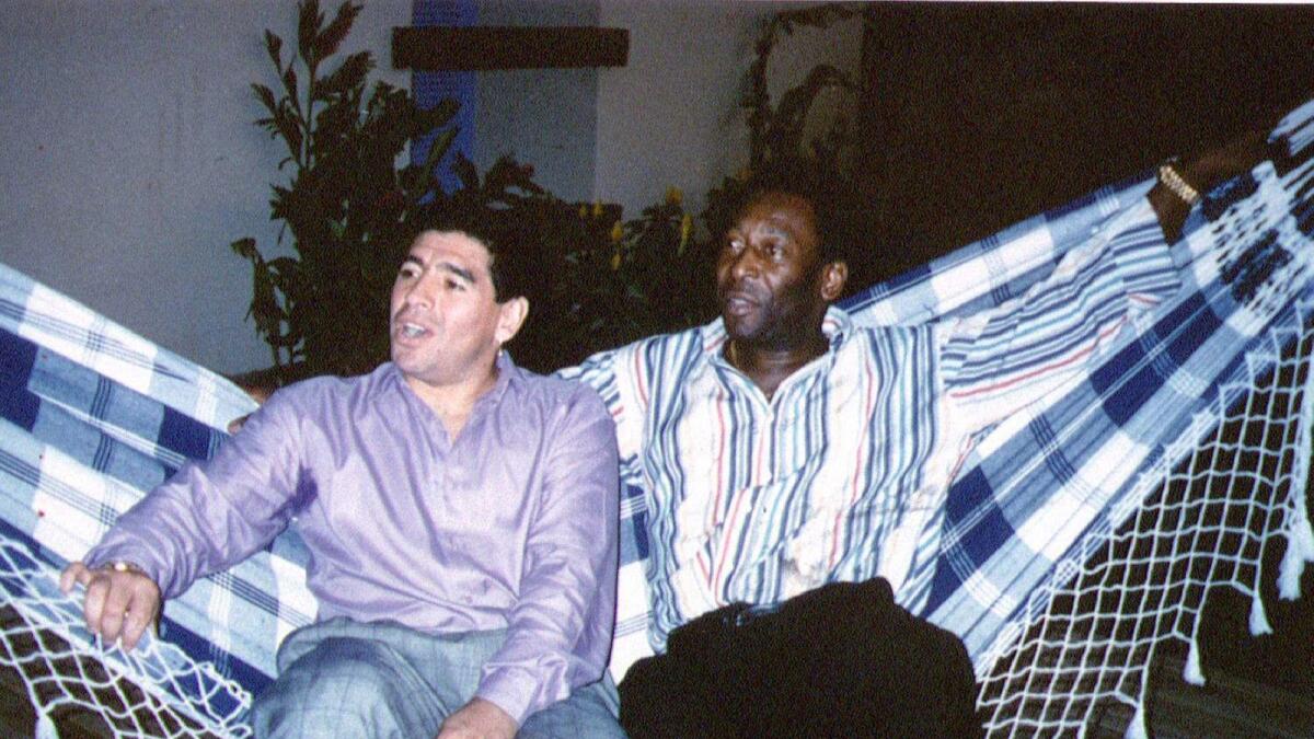 Soccer legends Diego Maradona and Pele rest on a hammock during a reception in Rio de Janeiro, Brazil, May 14, 1995. Reuters