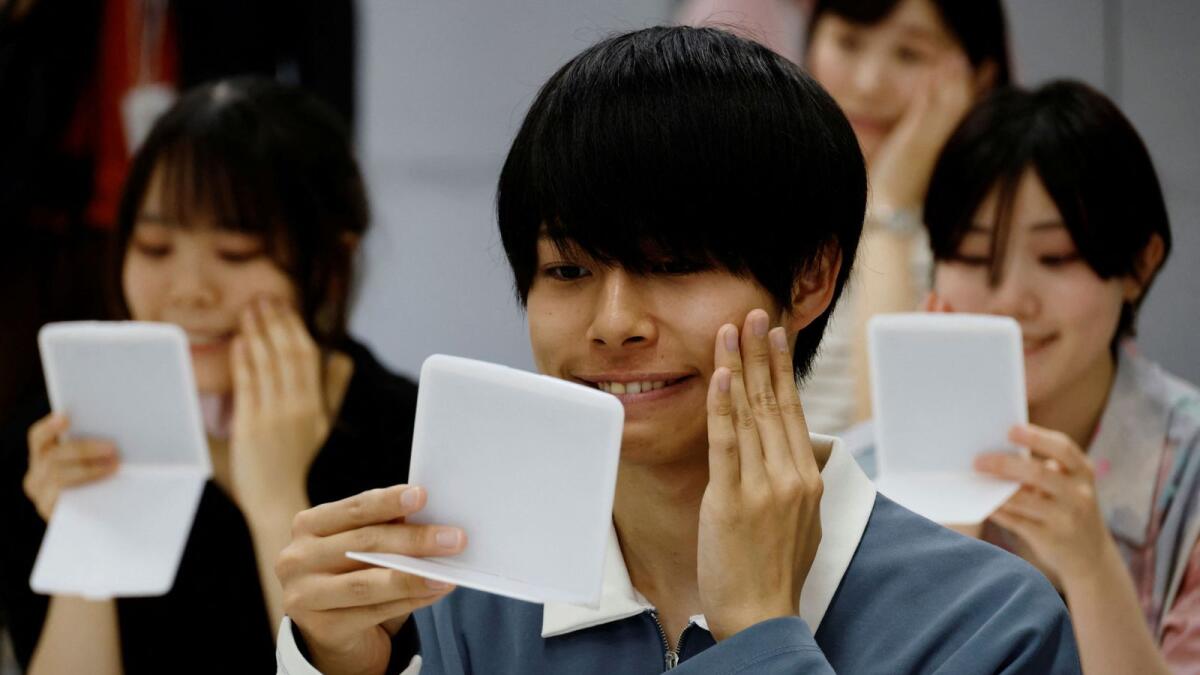 Students learn how to practice facial muscles with mirrors at a smile training course at Sokei Art School in Tokyo, Japan, May 30, 2023. -- Reuters file