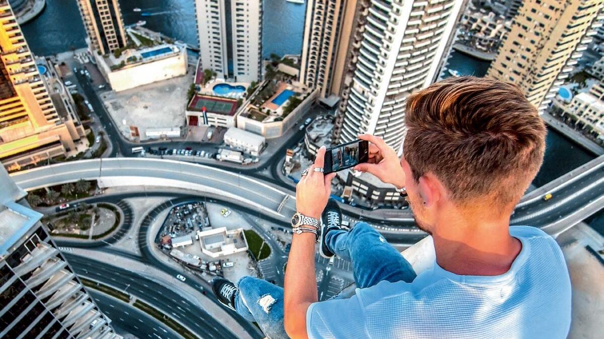 Dangerous Shot: Sitting precariously on top of the 43-storeyed Al Dar Tower is parkour artiste David Nelmes, who says years of training and experience are necessary for safe stunts. 