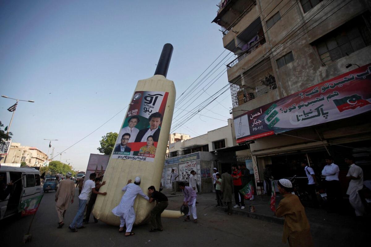 Supporters of Imran Khan, Pakistani cricketer-turned-politician and chairman of political party Pakistan Tehreek-e-Insaf (PTI), instal a giant bat symbol along a roadside in Karachi on May 4, 2013.  — Reuters file