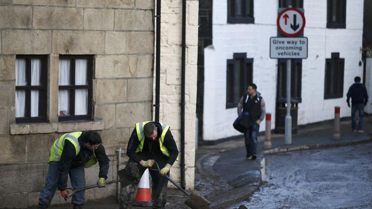 Men clear silt outside a home after flooding in the town of Mytholmroyd, northern England.