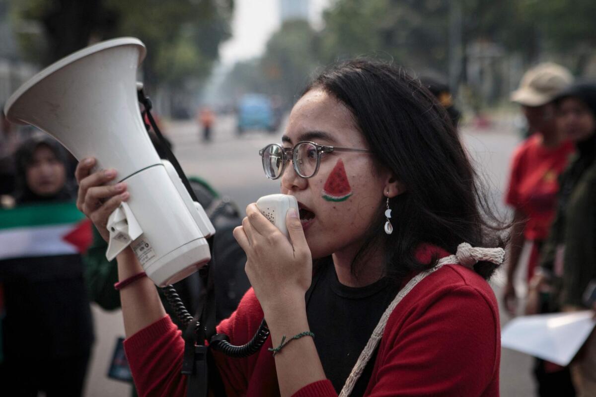A woman with a watermelon face paint shouts slogans into a megaphone during a protest in solidality with the Palestinian people in front of the US embassy in Jakarta on November 9, 2023. — AFP