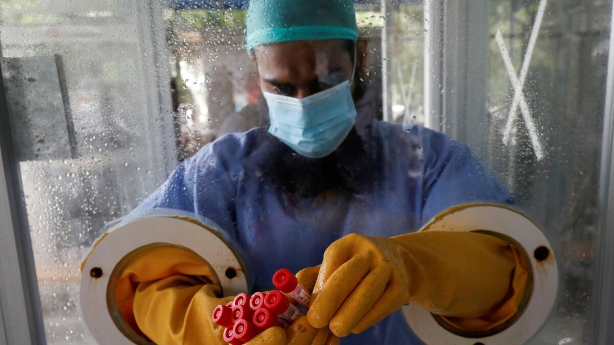 A paramedic wearing protective gear at a glass booth, counting nose-swab samples to be tested for the coronavirus disease (COVID-19), in Karachi, Pakistan June 26, 2020