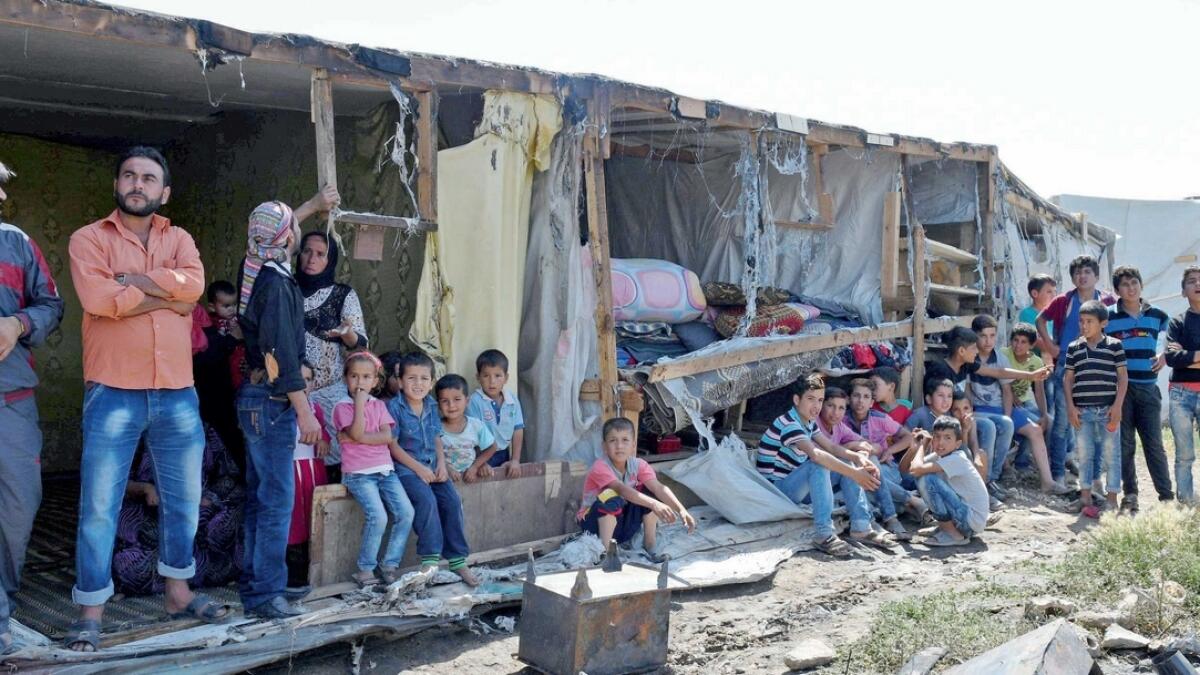 Syrian refugees near a damaged site after a fire broke out in their camp in Bar Elias town in the Bekaa valley Lebanon in July. Many refugees live in fear as they face assault from strangers.—Reuters