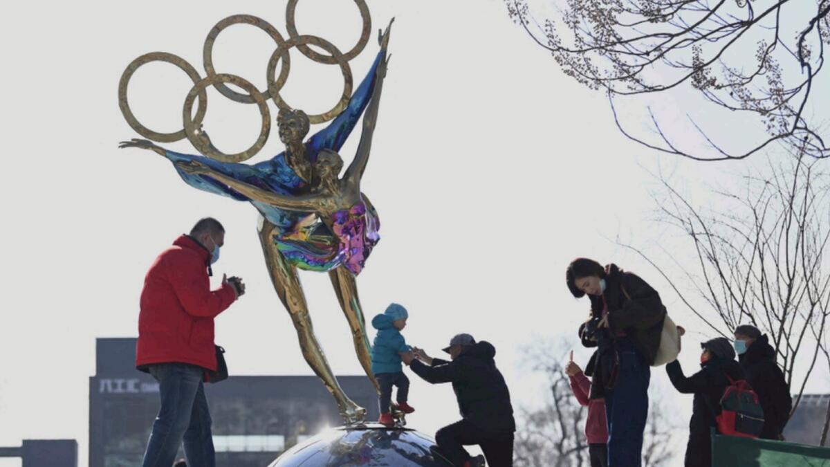 People walk past a statue with the Olympic Rings titled 'Dating With the Winter Olympics' by Huang Jian, near the headquarters of the Beijing Organizing Committee in Shougang Park. — AFP