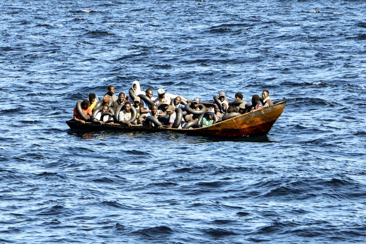 Migrants of African origin trying to flee to Europe are crammed on a small boat, as Tunisian coast guards prepare to transfer them onto their vessel, at sea between Tunisia and Italy, on August 10, 2023.  — AFP
