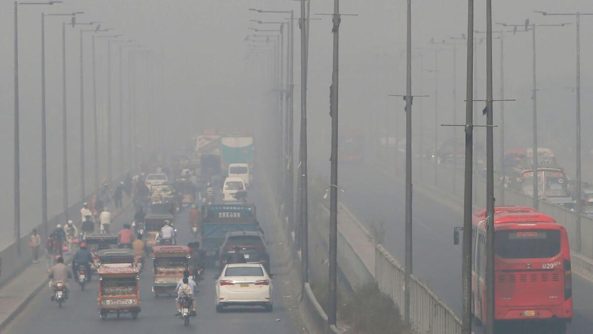 Vehicles drive on a highway as smog envelops an area of Lahore on Wednesday.