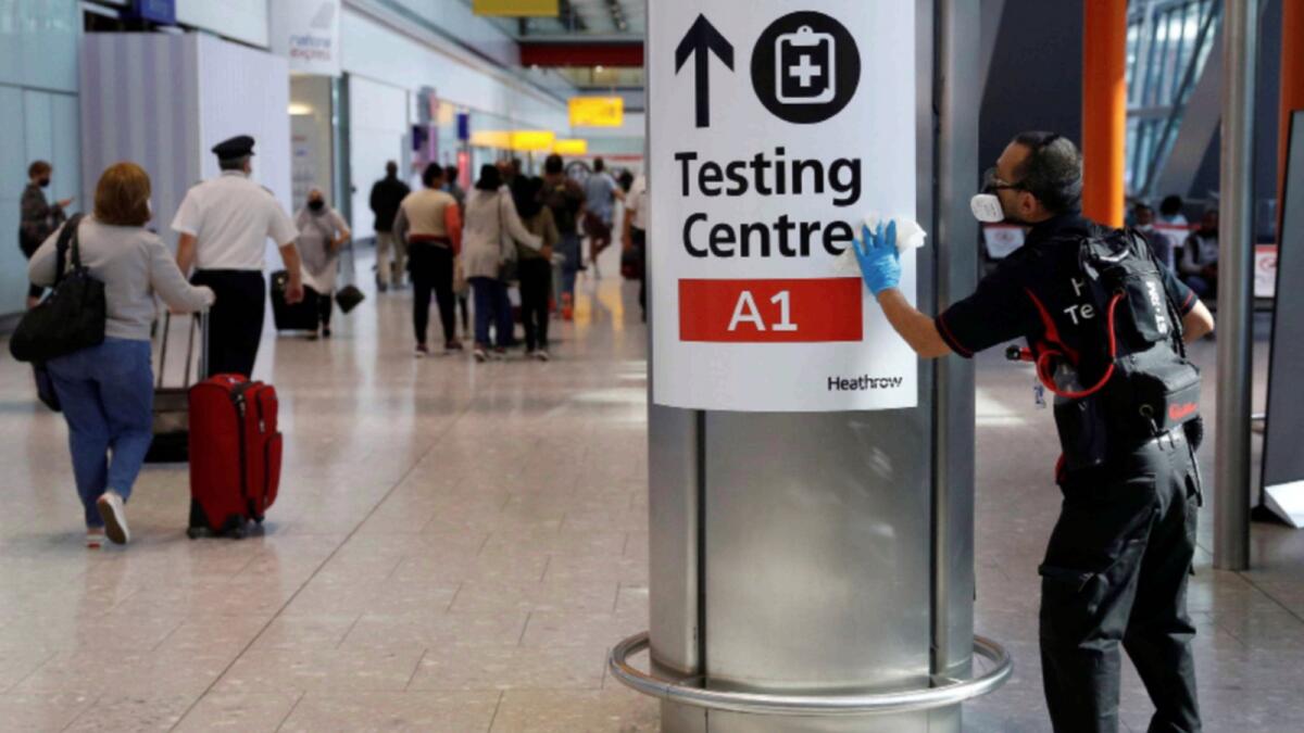 A worker sanitises a sign at the International arrivals area of Terminal 5 in London's  Heathrow Airport. — Reuters file