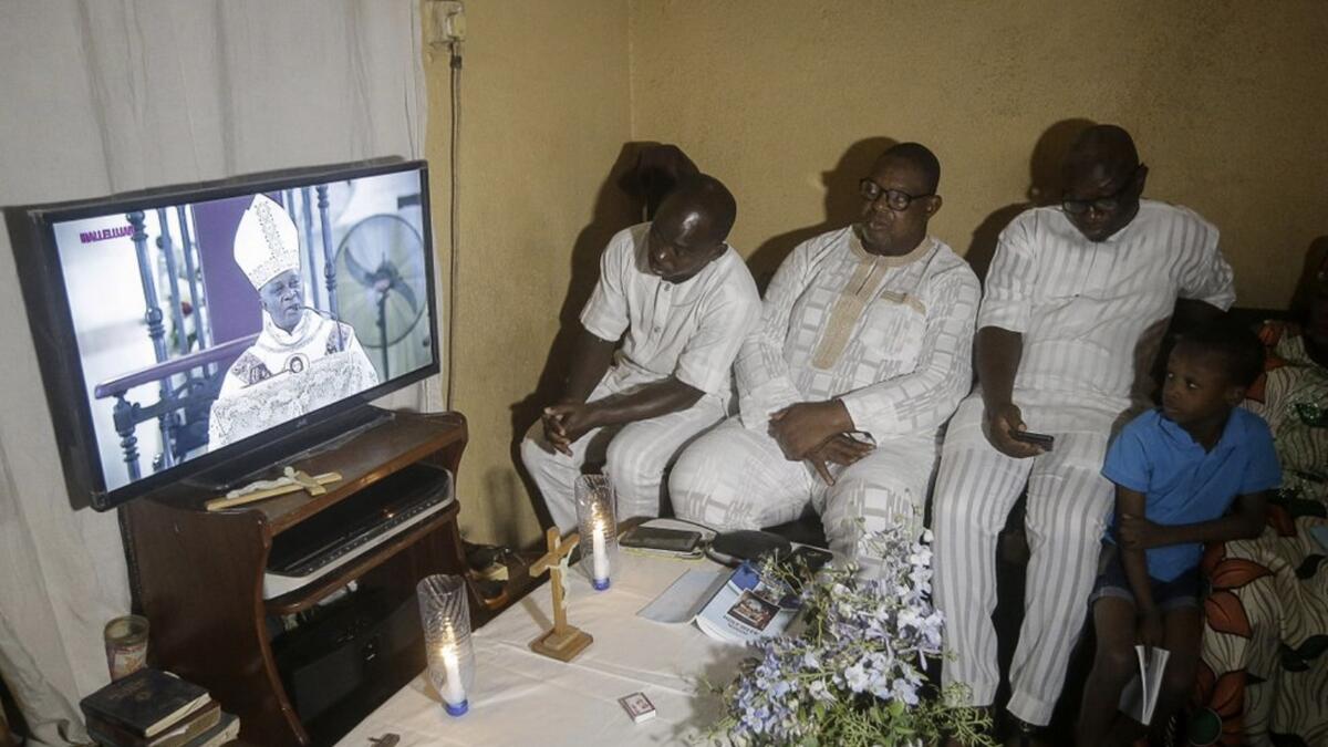 A family under lockdown watches a television broadcast of Archbishop of Lagos Alfred Adewale Martins conducting a service at the Holy Cross Cathedral, in their home in Lagos, Nigeria, on Easter Sunday. Photo: AP