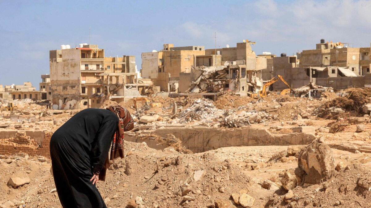 A survivor prays over the rubble of her destroyed house in Libya's eastern city of Derna. — AFP
