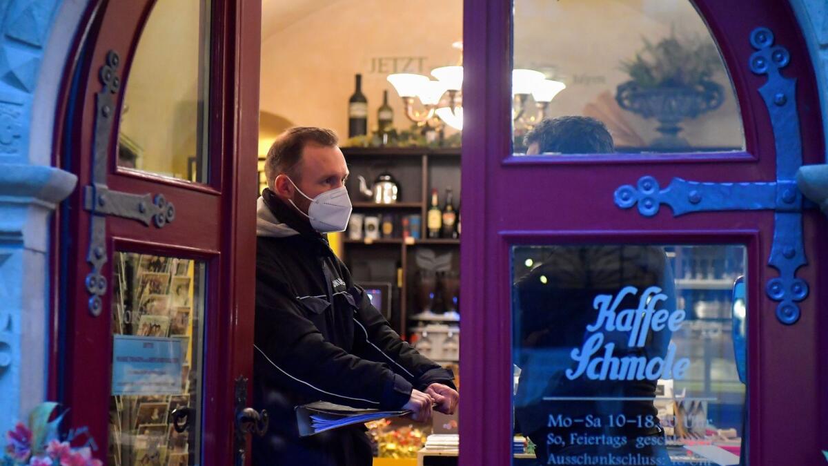 A member of the public order office checks the Covid-19 protocol at a coffee shop in Germany. (Reuters)