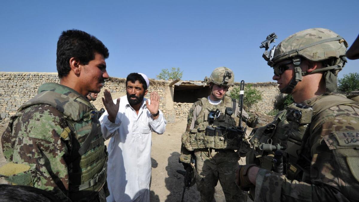 An Afghan soldier serves an interpreter as a civilian talks to US soldiers during a patrol  in eastern Afghanistan in this AFP file photo.