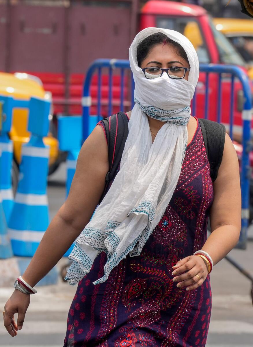 A young woman covering her face with a scarf to protect from the scorching heat walks on a road during a hot summer day in Kolkata on Tuesday. — PTI