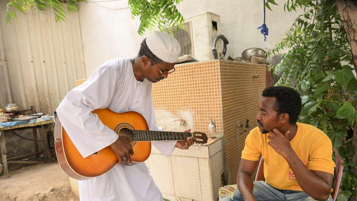 El Safi Mahdi, Sudanese music professor, plays guitar next to his friend, as he waits to travel to his Sudanese musician wife Sohair Saddig Ali, who fled the fighting following the crisis, at the theatre of Novelists and Artists Union in the city of Port Sudan on June 16, 2023. — Reuters